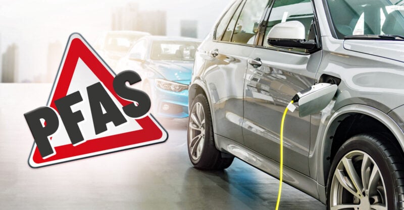Electric vehicle (silver car) being charged on the right with a pfas caution sign on the left.